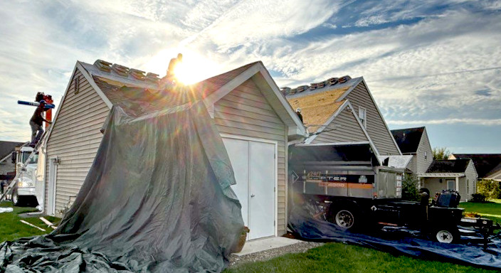 A roofer repairing a damaged shingle on a roof